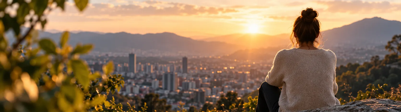 Persona contemplando el atardecer sobre Bogotá desde los cerros